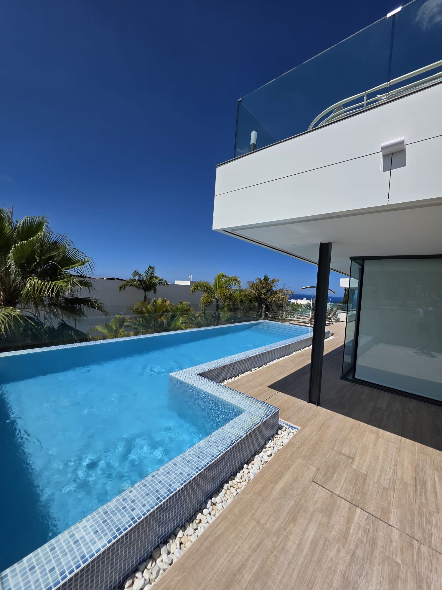 Infinity pool and stone deck alongside a completed villa